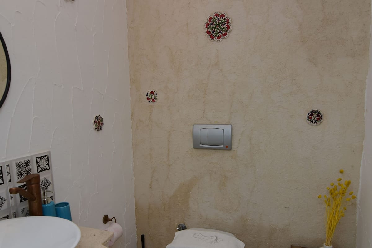 A bathroom with a white sink, toilet, and a small wooden table with a vase.