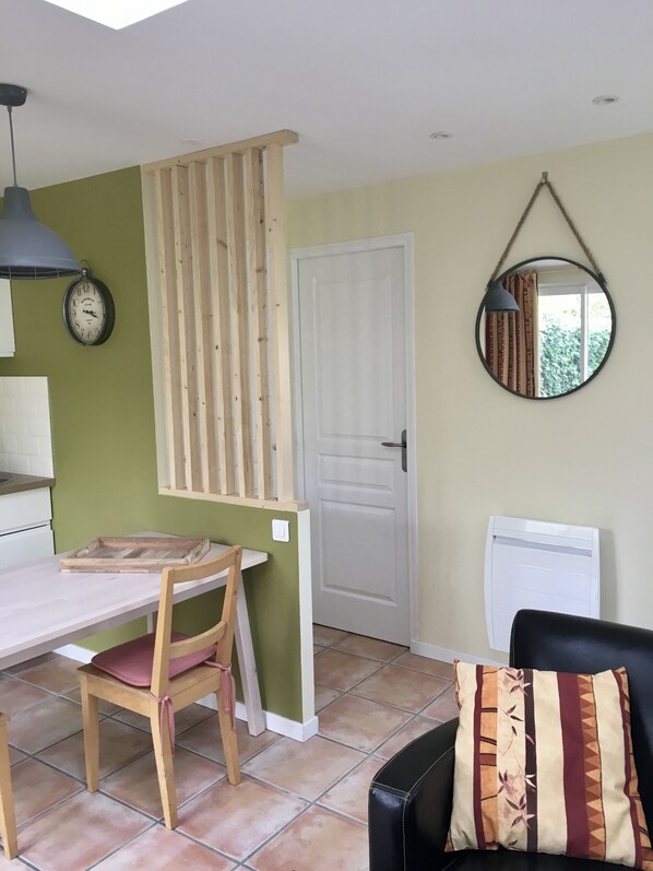 A room with a wooden table and chairs, a white door, a round mirror, and a clock on the wall. - Côté quai, charming gîte near Barbizon (Cély)