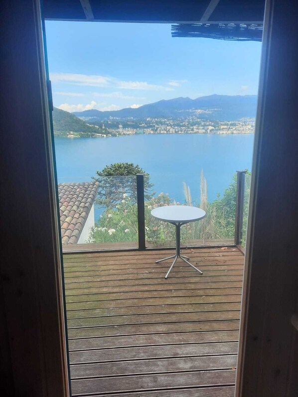 A wooden deck with a round table and a view of a lake and mountains.
