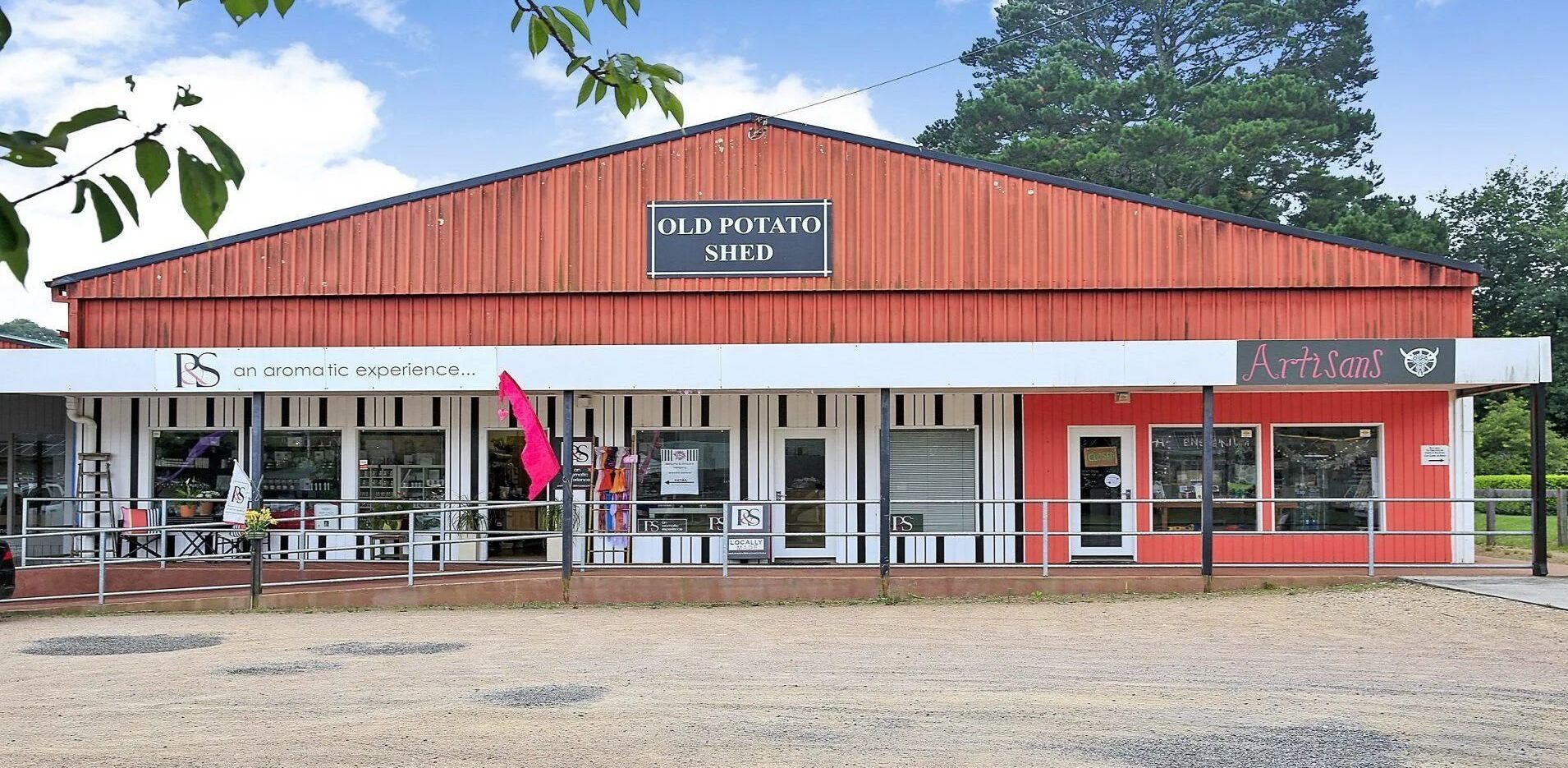 A red building labeled "Old Potato Shed" with a storefront named "Artisans."