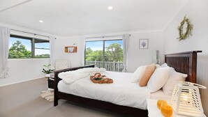 Un dormitorio con una cama grande, un balcón y vistas a árboles.