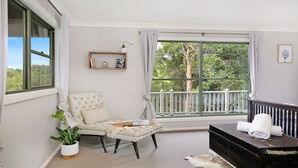 Una habitación con un ventanal grande, una silla, una mesita y un armario.