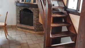 Eine Holztreppe mit Kamin, einem Holzstuhl und einem Fliesenboden.