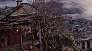 Ein traditionelles Gebäude mit einem Stein-Dach, einer Holztür und einem kleinen Vorbereich.