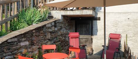 A stone patio with red folding chairs, a table, and a dog.