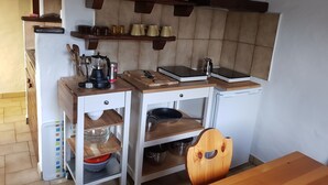Eine kleine Küche mit Holztischplatte, einer Kaffeemaschine, einem Wasserkocher und einem Schneidebrett.