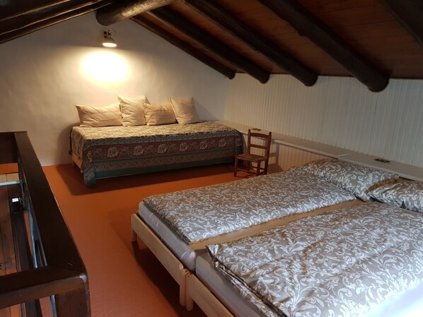 A bedroom with two beds, a chair, and a desk.