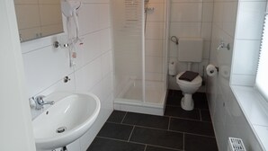 Een badkamer met een wit wastafel, toilet en een douche met glazen wanden.