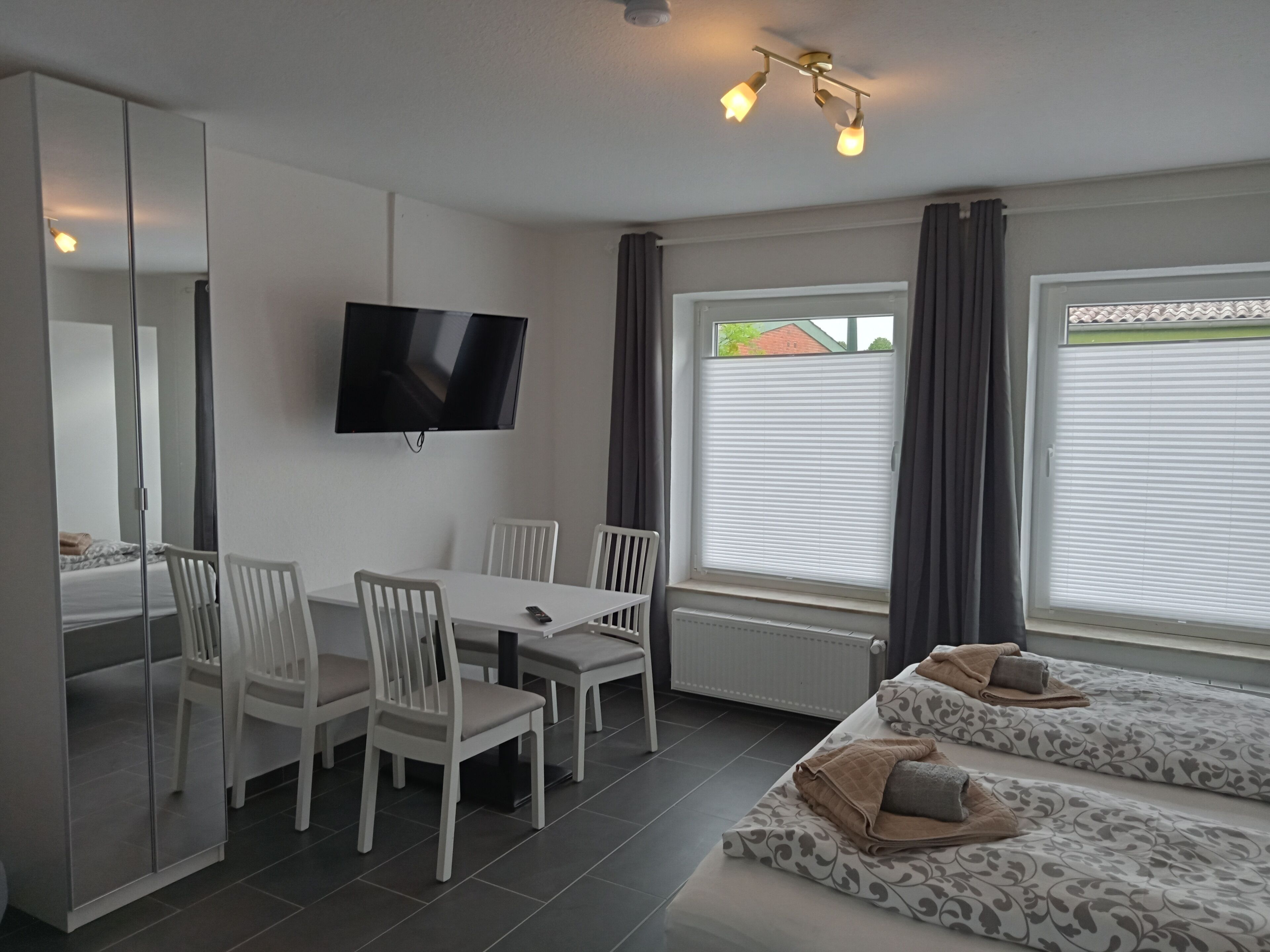A modern room with a TV, white furniture, and a bed with patterned bedding.