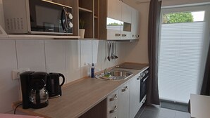 Een kleine keuken met een magnetron, koffiezetapparaat en wastafel.