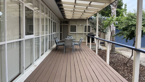 A covered outdoor deck with a table and chairs, surrounded by large windows. - Classic beach Getaway - Close to winery region and beach! (Dromana)