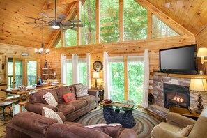 A spacious cabin interior with a large wooden ceiling, a fireplace, a television, and a dining area with a table and chairs. - 3 king suites, movie room, pool table, hot tub, view. (Gatlinburg)