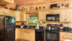 A wooden cabin kitchen with a refrigerator, stove, microwave, and wooden cabinets.