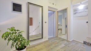 A hallway with a large mirror, a potted plant, and a door leading to another room.