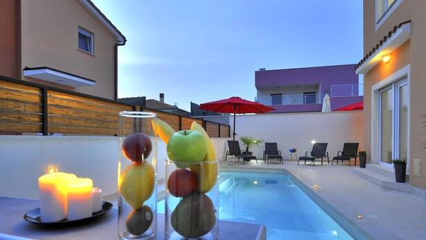 A poolside area with candles, fruit, and lounge chairs.