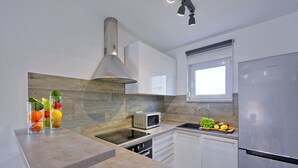 A modern kitchen with a built-in microwave, stainless steel refrigerator, and a window above the sink.