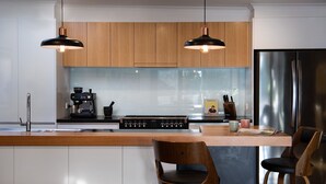 A modern kitchen with wooden cabinets, a stainless steel refrigerator, a coffee machine, and two pendant lights.