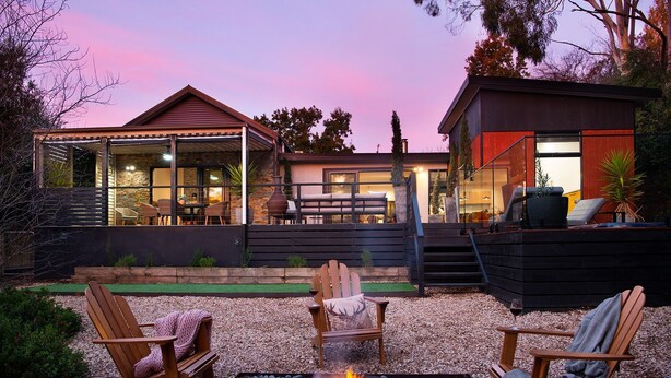A modern house with a covered patio, outdoor seating, and a fire pit.