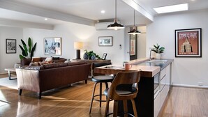 A modern kitchen with a central island, bar stools, and pendant lighting.