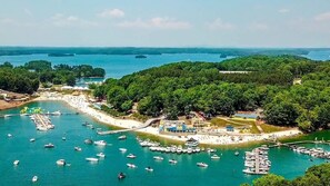 Une zone côtière dotée d’un port de plaisance, de bateaux et d’une colline boisée.