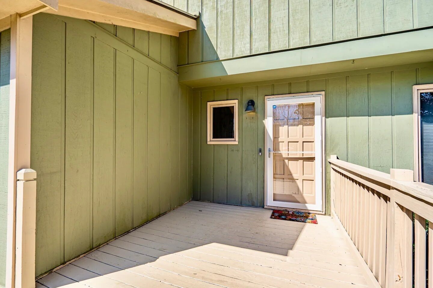 Un espace extérieur abrité doté d’une terrasse en bois, d’une porte-fenêtre coulissante et d’une petite fenêtre.
