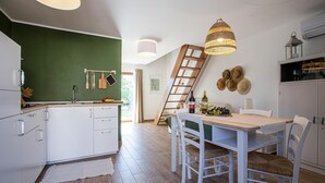 Une cuisine moderne avec des meubles blancs, une table à manger en bois et un mur d’accent vert.