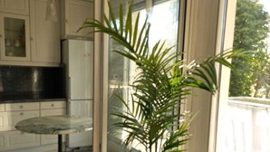 Een keuken met witte kasten, een glazen tafel en een potplant.