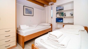 A bedroom with two wooden beds, a wardrobe, and a shelf with decorative items. - Apartment Ribambit (Dubrovnik)
