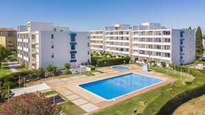 Un immeuble d’appartements moderne doté de nombreux balcons, d’une piscine centrale et de jardins bien entretenus.