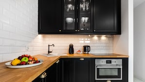 A modern kitchen with black cabinets, a wooden countertop, a built-in oven, and a fruit bowl.