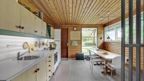 A compact kitchen with wooden cabinets, a sink, and a dining area with a table and chairs. - Amazing home in Nykøbing M (Nykøbing M)