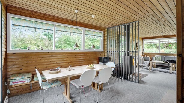 A wooden cabin interior with a dining area, a kitchen, and a seating area with a view of the outdoors. - Amazing home in Nykøbing M (Nykøbing M)