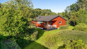 A red cabin with a porch, surrounded by lush greenery. - Amazing home in Nykøbing M (Nykøbing M)