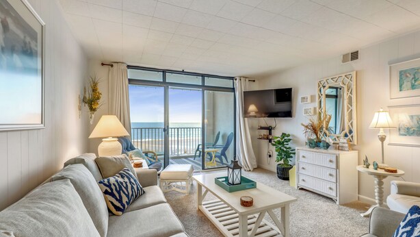 A spacious living room with a large window, a sofa, a coffee table, and a television.
