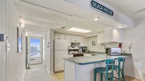 A kitchen with a central island, a clock, and a sign that reads 'Beach House.'