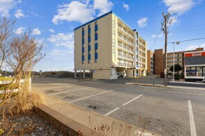 Un hôtel à plusieurs étages, doté d’une façade sobre, d’un parking et surplombant un ciel dégagé.