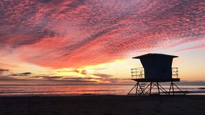 A lifeguard tower on a beach with a sunset in the background.