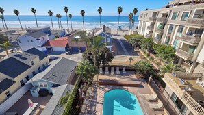 A residential area with a swimming pool, palm trees, and a view of the ocean.