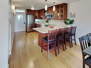 Una cocina moderna con armarios de madera, electrodomésticos de acero inoxidable y una isla central con taburetes de bar.