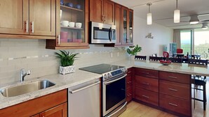 A modern kitchen with wooden cabinets, a stainless steel refrigerator, an oven, and a dishwasher. - Luxurious Kihei Remodeled 2BR Condo Sweeping Ocean Views Near Keawakapu (Kihei)