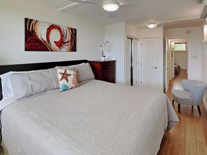 Un dormitorio con una cama grande, una mesita de noche, una silla y una puerta que da a otra habitación.