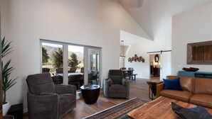 A spacious living room with a large sliding glass door leading to a patio, a cozy seating area with a sofa and armchairs, and a dining area with a table and chairs.