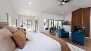 A spacious bedroom with a large bed, a ceiling fan, and a fireplace.
