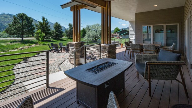 A covered outdoor patio with stone seating, a fire pit, and a view of a green landscape.