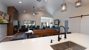 A spacious living area with a large sofa, a dining table, and a kitchen with a modern sink.