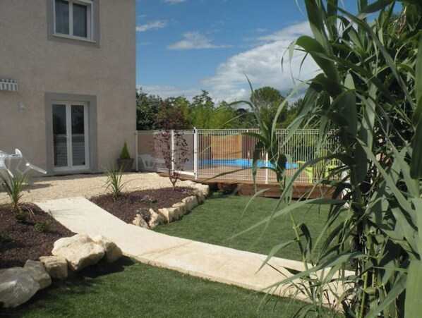 Enjoy a serene outdoor space with a pool, lush garden, and a pathway leading to the two-story residence.