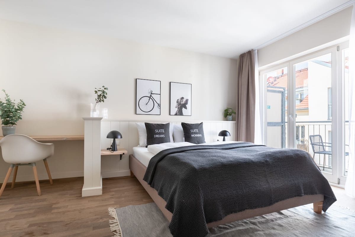 Une chambre moderne avec un lit, des tables de chevet, un bureau, une chaise et une vue sur le balcon.