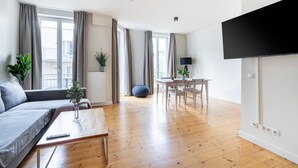 Ein modernes Wohnzimmer mit einer Couch, einem Couchtisch und einem Essbereich mit Tisch und Stühlen.
