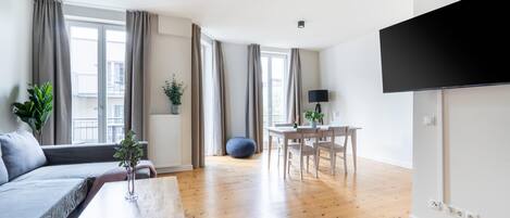 A modern living room with a sofa, coffee table, and a dining area with a table and chairs.
