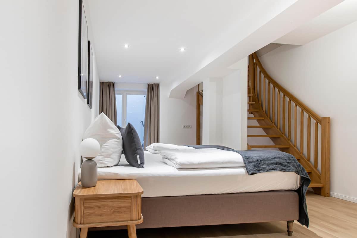 Une chambre à coucher avec un lit, une table de chevet en bois et un escalier.